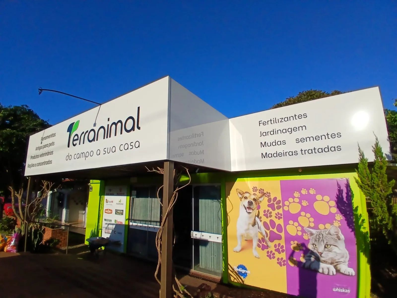 Fachada branca em ACM da loja Terranimal com a frase do campo a sua casa e lista de produtos